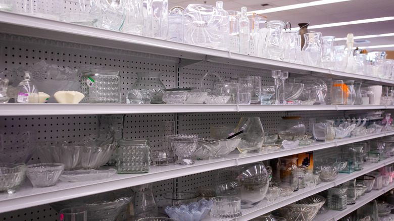 The glass section at a thrift store full of plates, bowls, and vases.