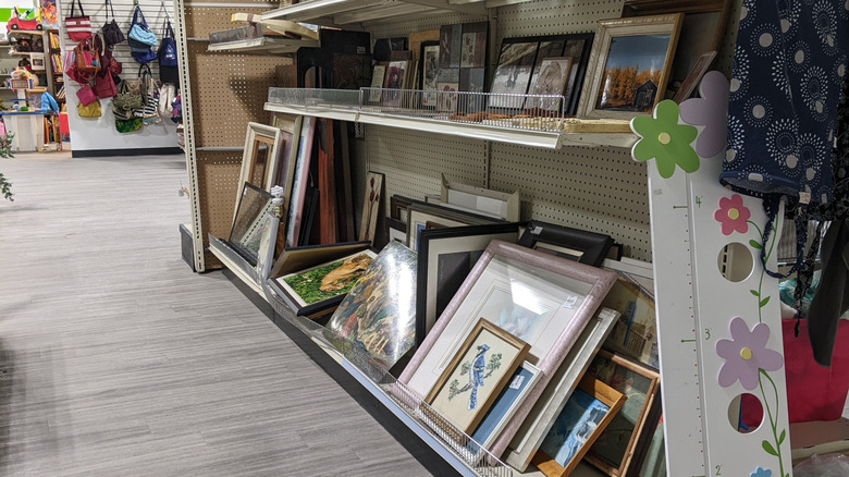 stacks of picture frames in a thrift store aisle