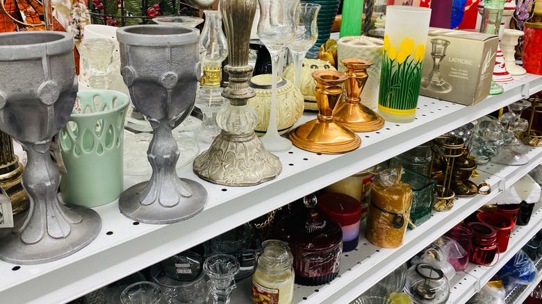 candles and other items on shelves in a thrift store