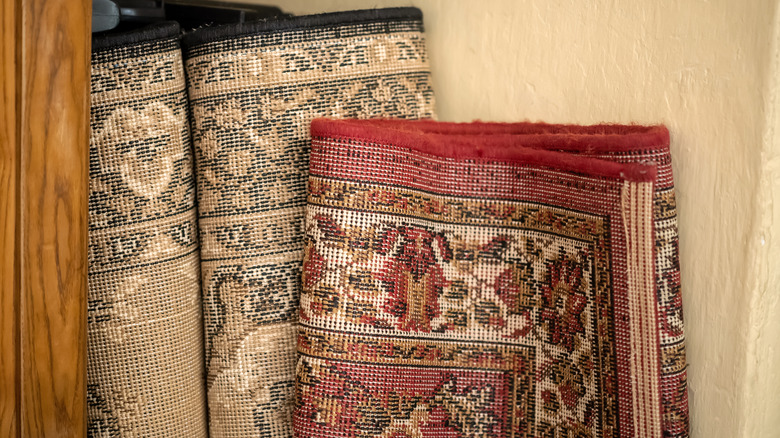 two vintage area rugs leaned up against a wall