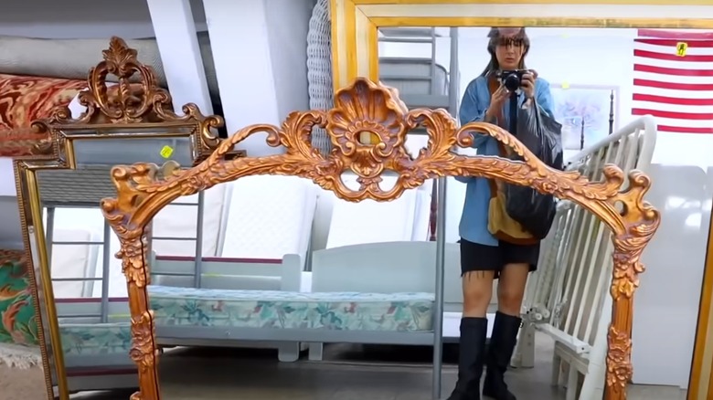 three thrift store mirrors reflect a woman holding a camera
