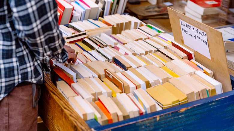 person looking through a crate of books at a thrift store