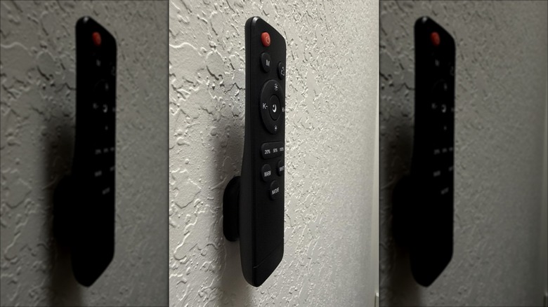 black TV remote mounted to wall using magnetic holder