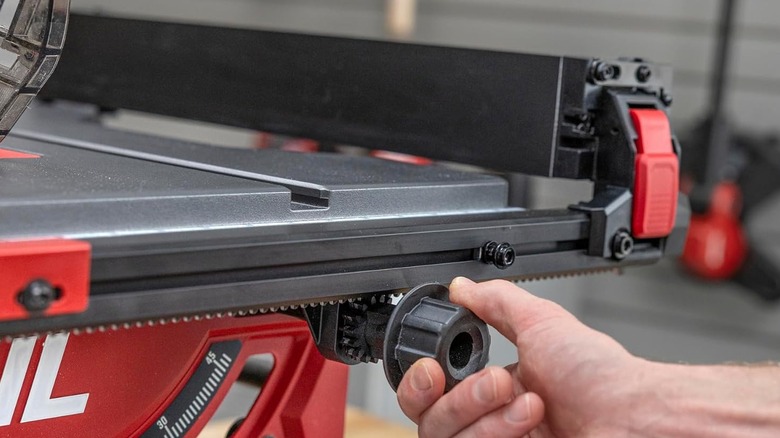 A person is adjusting the fence on a table saw