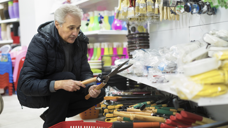 A person shops for gardening tools in a hardware store.