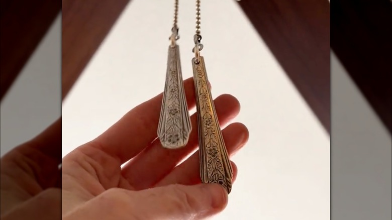 A person holds spoon handles used as the end pieces on a ceiling fan pull chain.