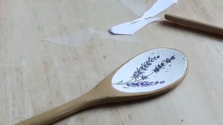 A wooden spoon with white-painted bowl featuring a lavender painting.