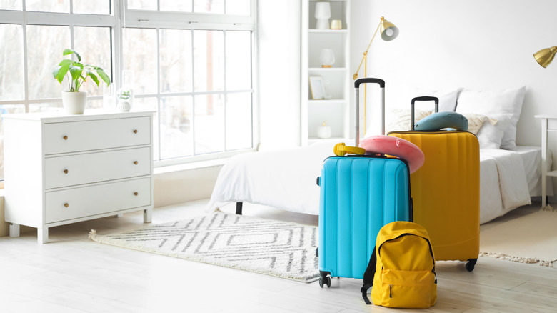 Organized guest bedroom with luggage and backpack on the floor.