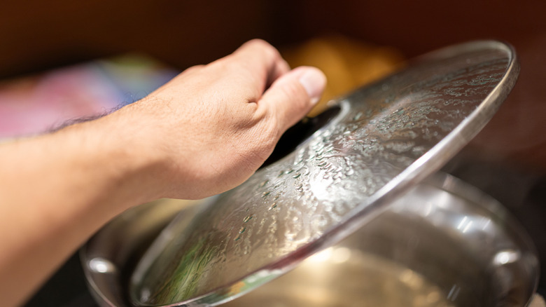 person picking up pot lid