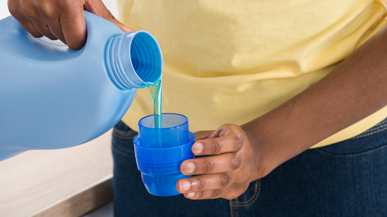 hands pouring detergent into cap