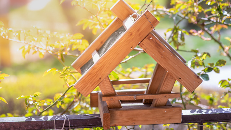 New wooden bird feeder perched on a porch railing
