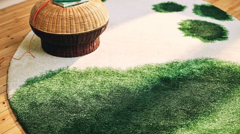 green and off-white rug on floor with rattan foot stool