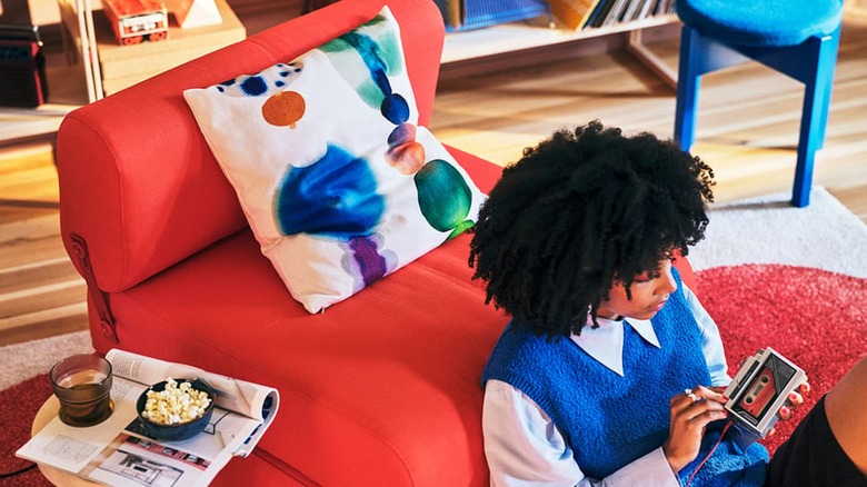 girl leaning against red chair with multi-color pillow