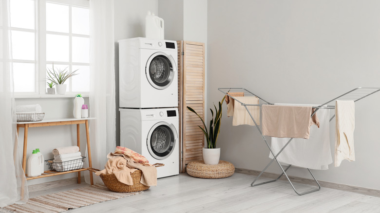 A stacked washer and dryer combo sit in the corner of a laundry room.