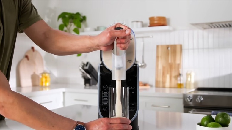 Man in kitchen using Ninja SLUSHi to to pour drink into glass