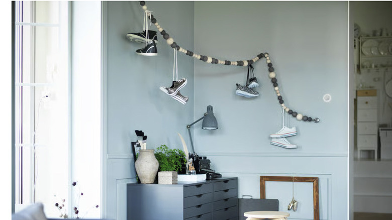 A wavy blue and white beaded hanging pole with trainers looped over it by their laces.