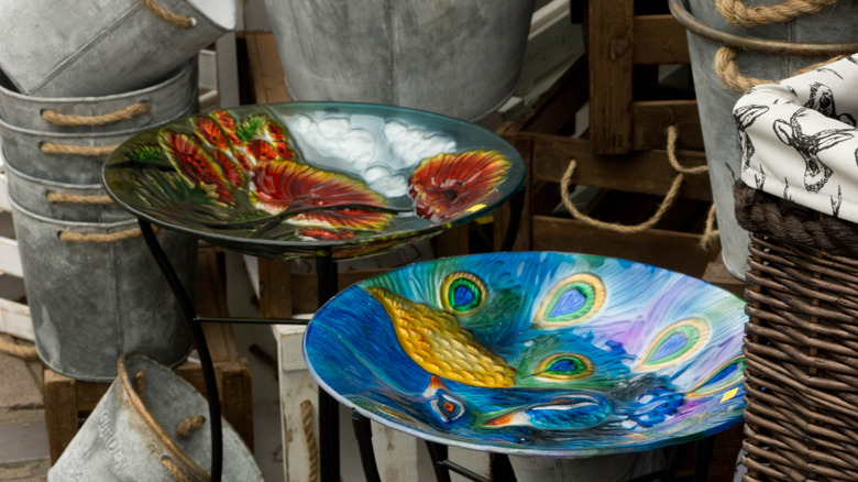 Ornate metal birdbaths and other garden supplies at a market stall.