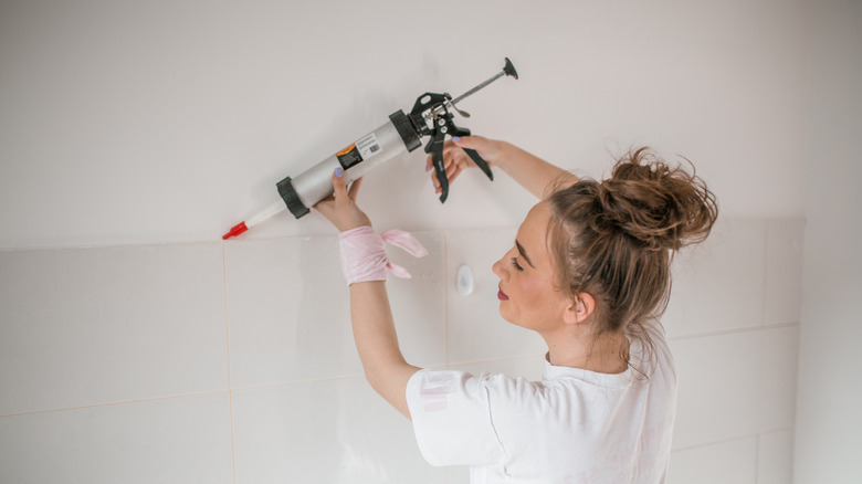 Woman using a caulk gun on a wall