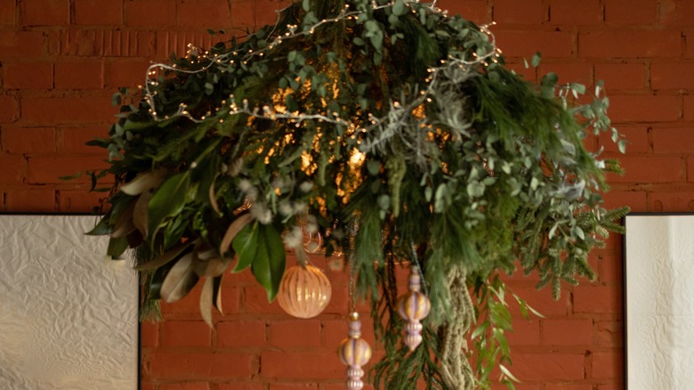A chandelier decorated with greenery and ornaments for Christmas
