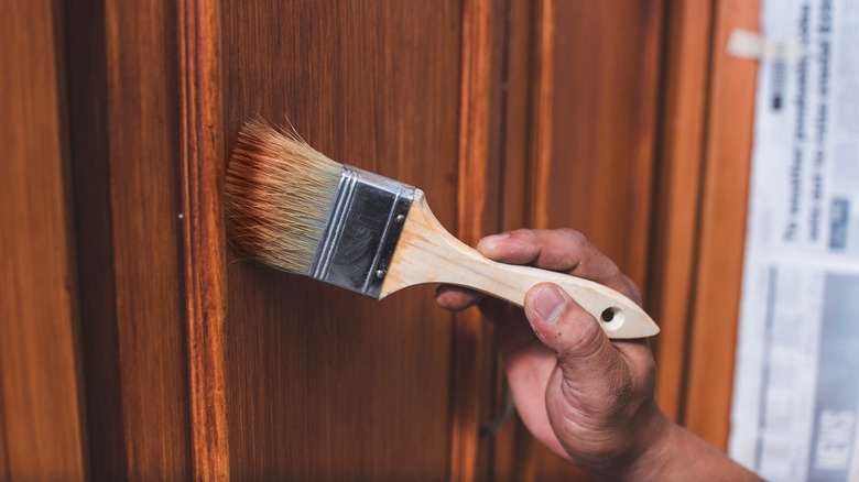 Hand painting wood stain on cabinet