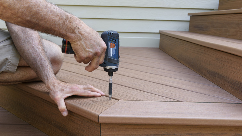 Plank deck with stone border and patio chairs in background
