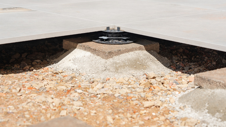 A paved terrace under construction, with pedestals beneath the pavers