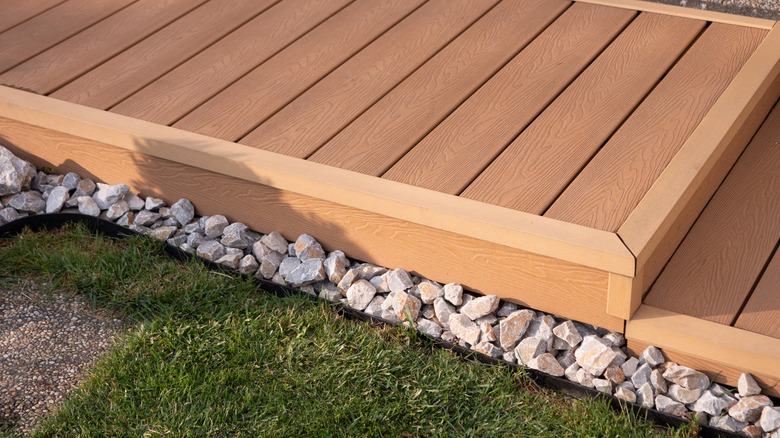 A natural-looking wood-plastic-composite decking next to rock border and lawn