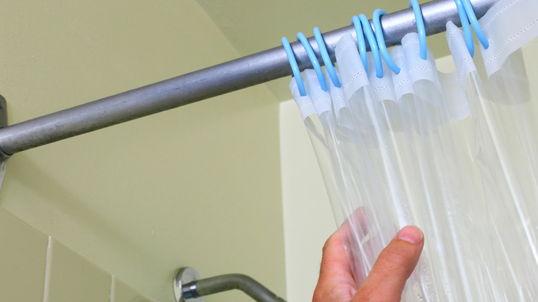 person closing plastic shower curtain