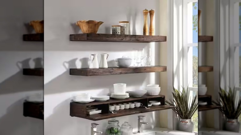A trio of floating shelves with kitchen items. The bottom shelf's front is hinged open to reveal items