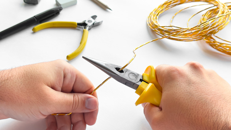 A person bending craft wire to make an armature for sculpting with air-dry clay.