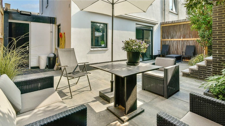 A modern patio setup behind a white house.