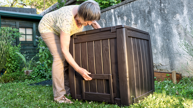 person holding a bulky plastic storage box in backyard