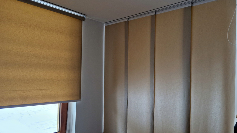 Tan panel track shades cover a sliding glass door in a home.