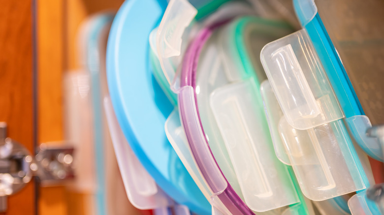 Precariously stacked food storage container lids in a kitchen cabinet