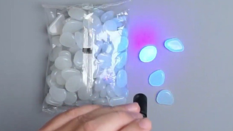 Person showing how adding light causes pebbles to glow