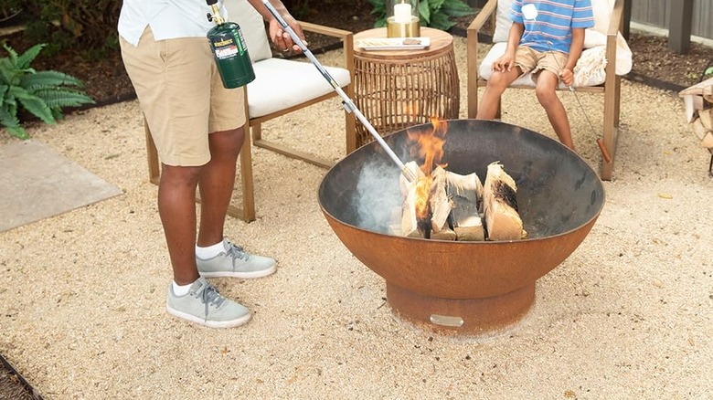Person lighting a fire pit with the Bernzomatic weed torch
