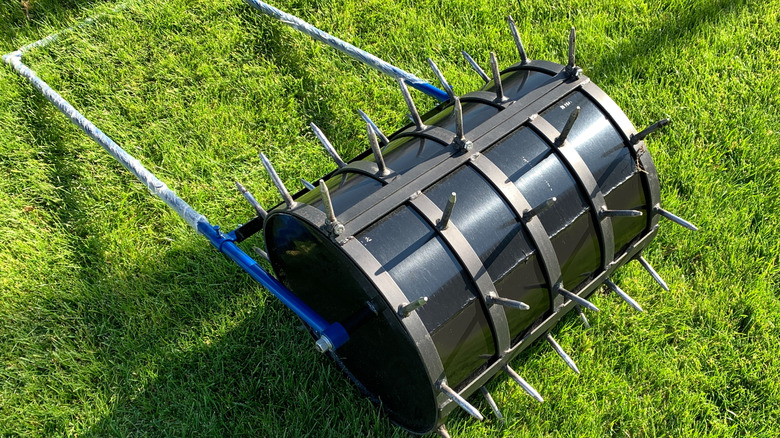 A manual lawn aerator with a large drum and many spikes