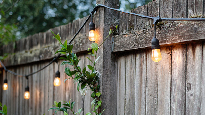 A series of string lights along a wooden fence outdoors