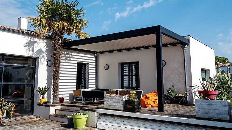A modern pergola provides shade for a raised deck area