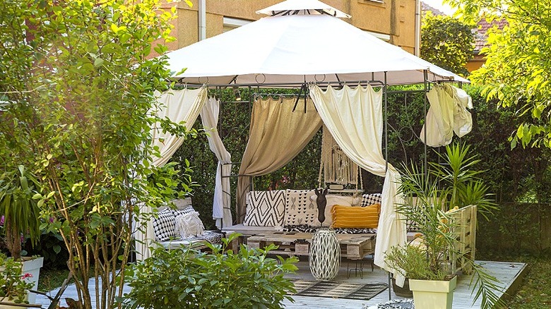 A gazebo covers a concrete-covered area of a backyard