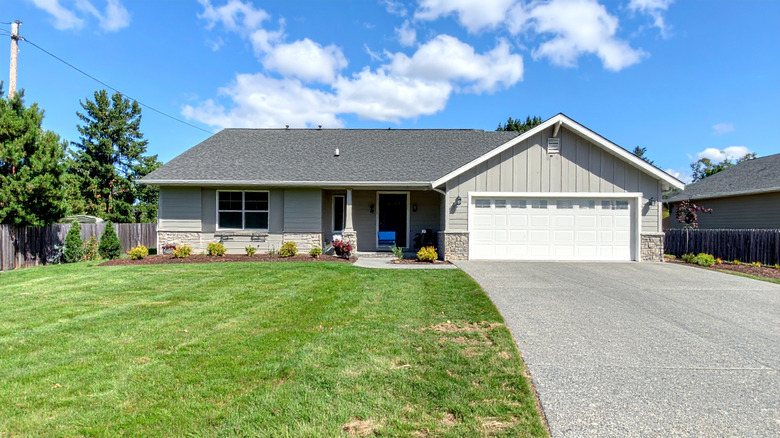 a white home with a long concrete driveway and grass lawn