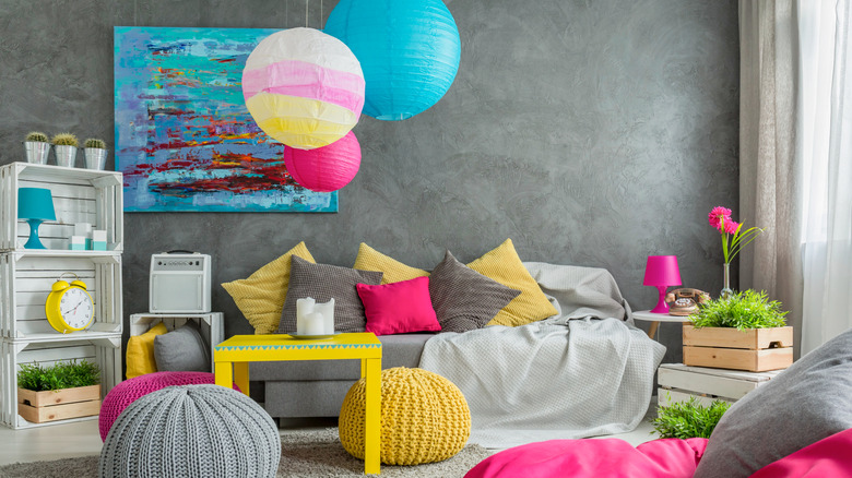 A living room with white floors and limestone gray walls with lots of pinks, blues, and yellows throughout the room