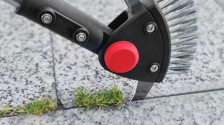 Closeup of the BARAYSTUS crevice weeder, its thin blade digging out weeds from a narrow crack between paver stones