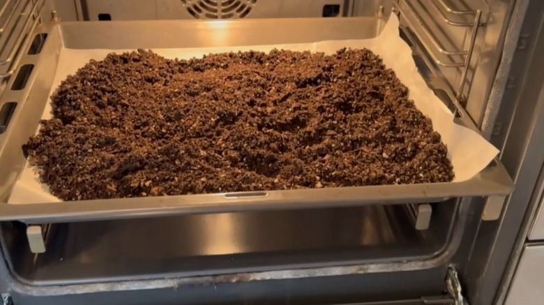 potting soil spread out on a large tray inside an oven