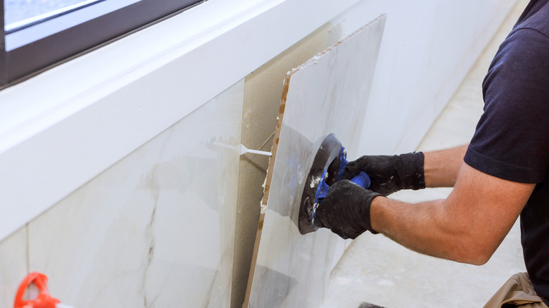 man using suction cup to install tile on wall