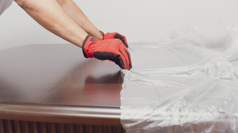 Person placing plastic dust cover on table