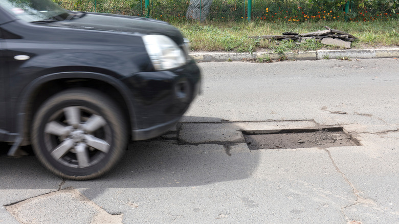 Car passing by a pothole.