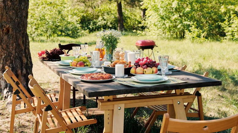 Group of chairs surrounding wooden festive table in a garden