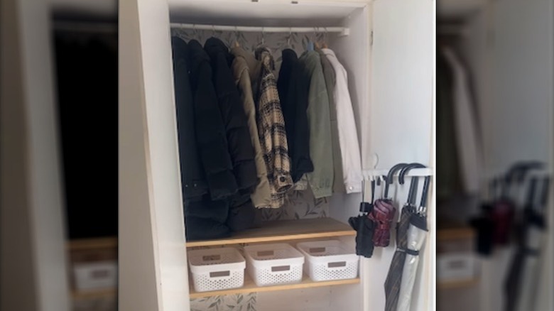 A well-organized closet with hanging clothes, plastic bins, and an IKEA towel rack on the side wall.