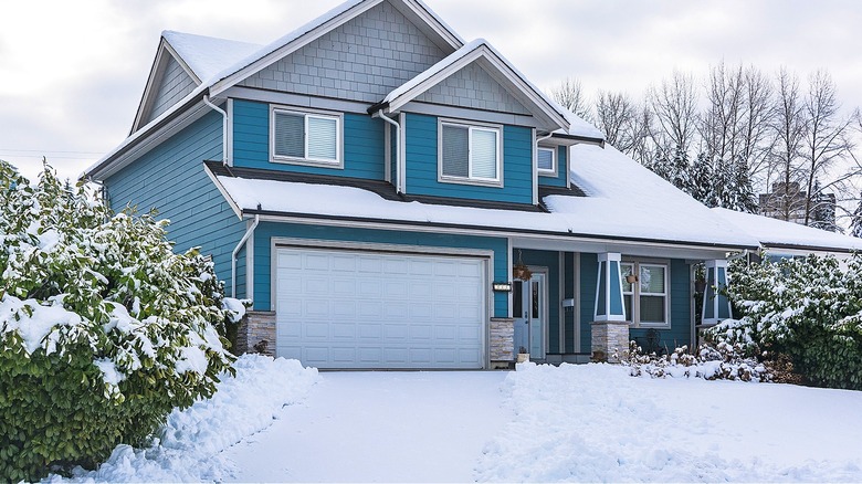 Snow-covered driveway and blue house
